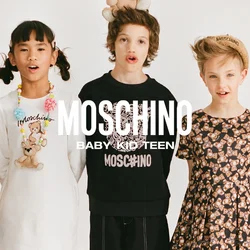 Cinque bambini vestiti con abiti Moschino stanno in fila, ognuno con un orsacchiotto come accessorio sulla testa o sul vestito.