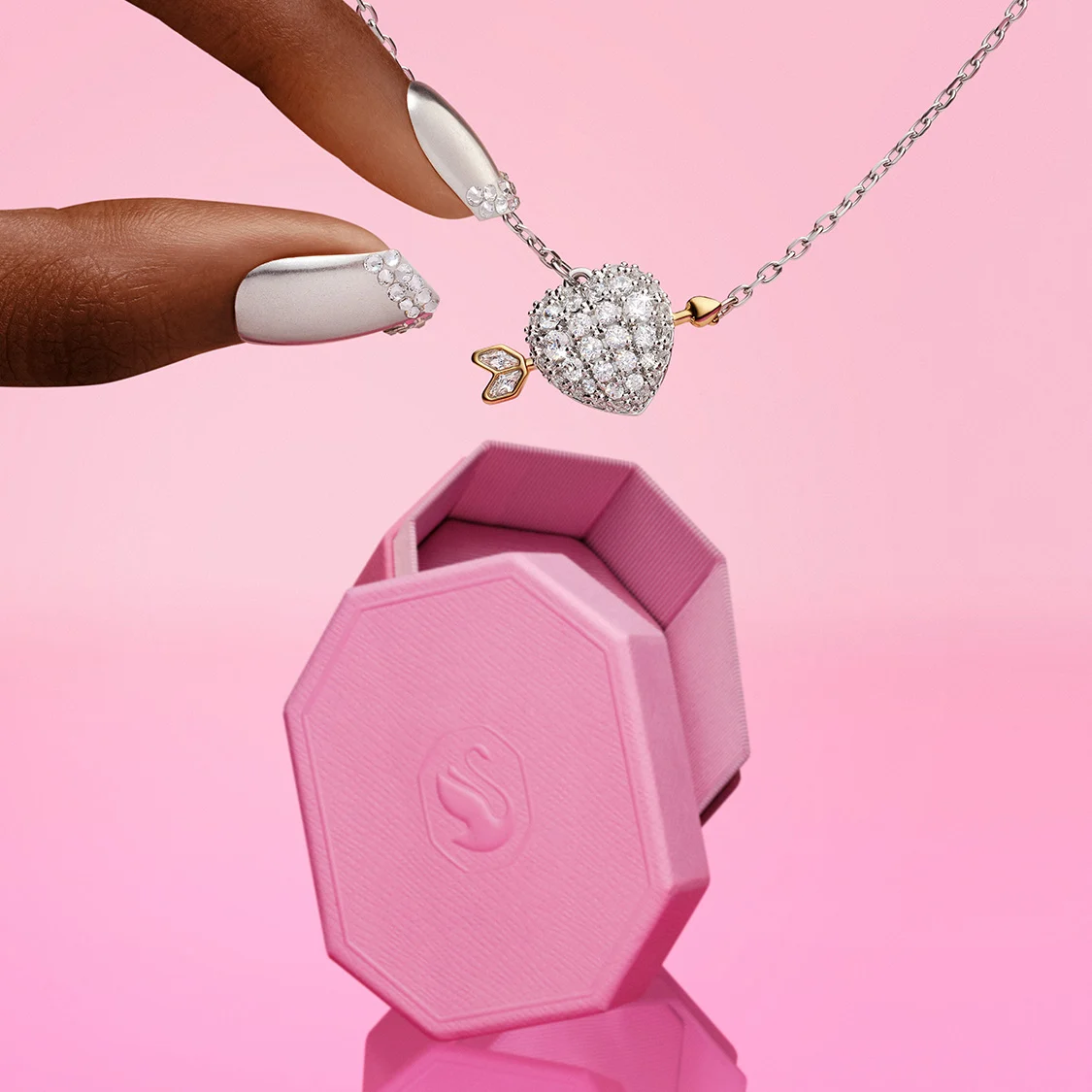 Dita che stanno per prendere un pendente Idyllia a forma di cuore