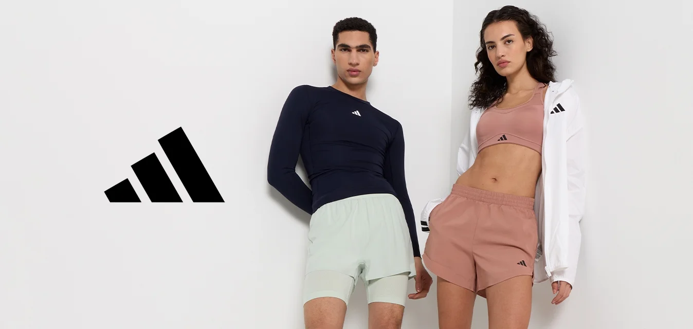 Due modelle indossano abbigliamento sportivo: una maglia a maniche lunghe blu navy, pantaloni corti mint, e un crop top rosa chiaro abbinato a pantaloni corti marroni, con una giacca bianca.