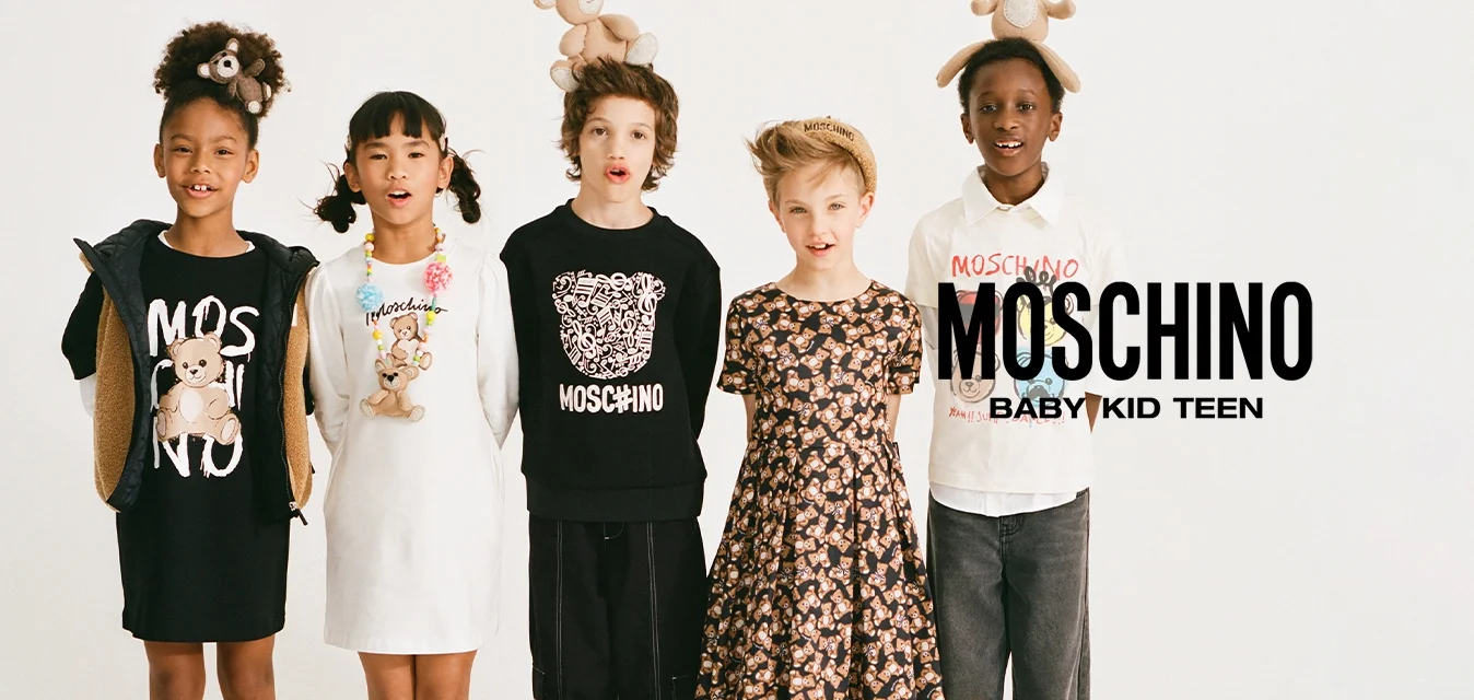 Cinque bambini vestiti con abiti Moschino stanno in fila, ognuno con un orsacchiotto come accessorio sulla testa o sul vestito.