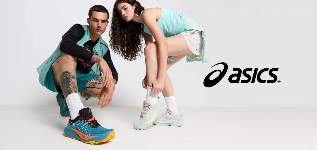 Sneakers sportivi con parte superiore in rete; uno in teal con accenti arancioni e neri, l'altro in verde chiaro con dettagli pastello. Due modelli in posizione accovacciata.