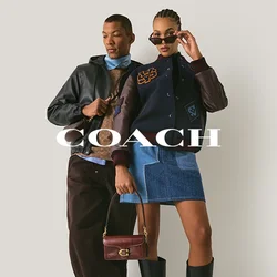 Due modelli posano contro un muro semplice; uno indossa una giacca di pelle, pantaloni marroni e sneaker, l'altro una giacca varsity, una gonna di jeans, stivali e occhiali da sole.