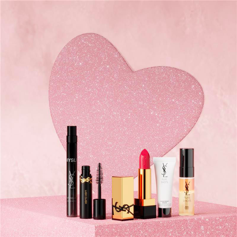 Una selezione di prodotti per il trucco e la cura della pelle YSL esposti davanti a un cuore rosa scintillante.