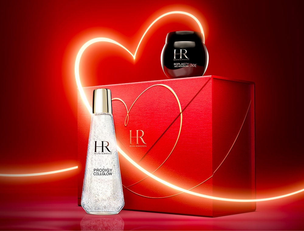 Immagine dei prodotti Age Recovery Night e Dewy Essence con un nastro luminoso a forma di cuore che avvolge una confezione regalo rossa con un disegno a cuore simile
