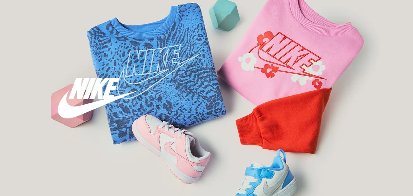 Felpe Nike piegate blu e rosa con logo, due scarpe da bambino in rosa e blu, blocchi geometrici rossi e blu su sfondo beige.