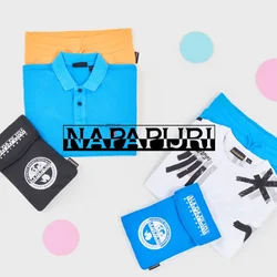 Polo shirt blu piegato su pantaloni corti arancioni e t-shirt grafica bianca su pantaloni corti blu con mascherine piegate nere e blu su sfondo bianco.