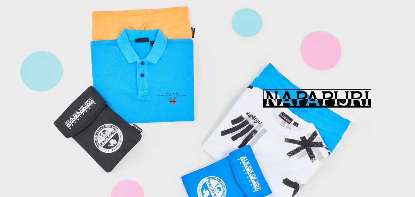 Polo shirt blu piegato su pantaloni corti arancioni e t-shirt grafica bianca su pantaloni corti blu con mascherine piegate nere e blu su sfondo bianco.