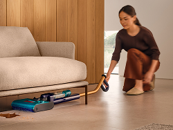 Il Dyson Clean+Wash Hygiene utilizzato per pulire sotto un divano basso.