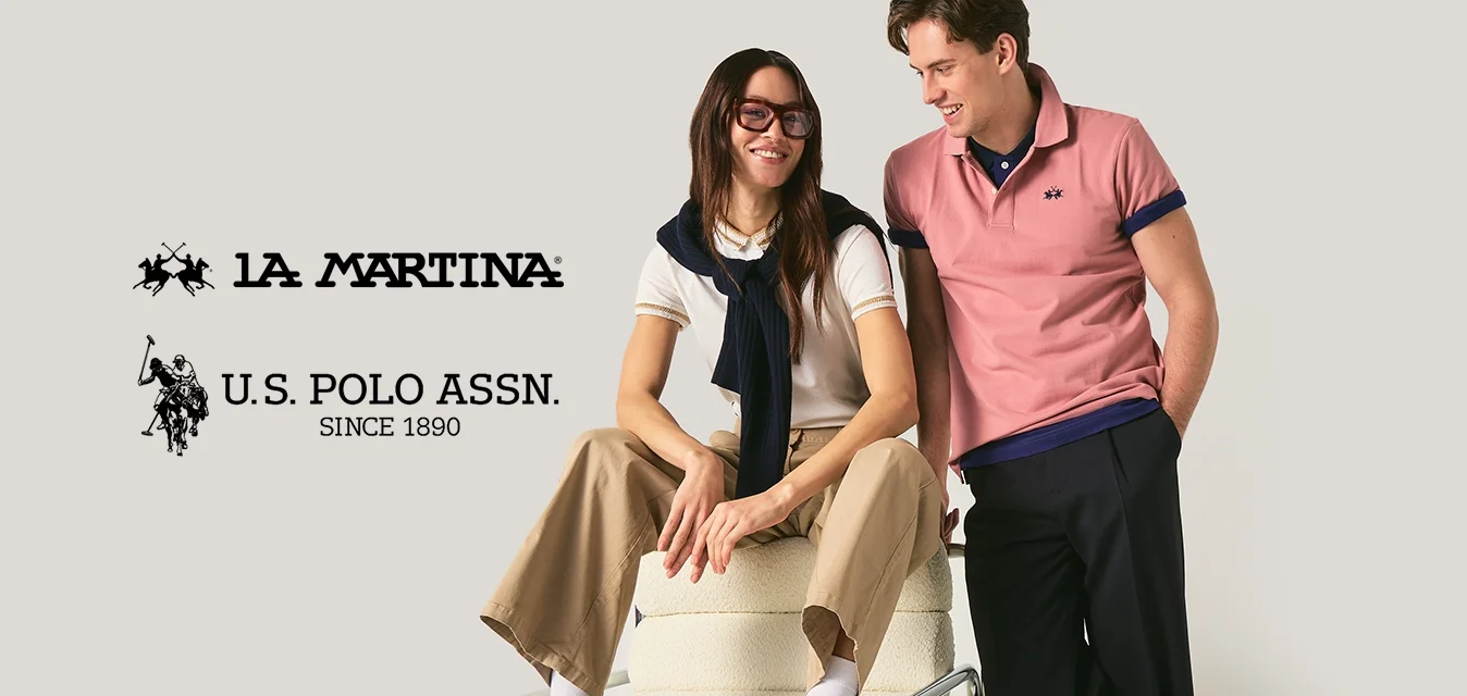 Giovane donna seduta su una sedia con occhiali e abbigliamento casual, giovane uomo in piedi accanto a lei che sorride appoggiandosi alla sedia.