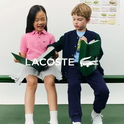 Due bambini seduti su una panchina verde che leggono libri rilegati verdi, con un poster di un coccodrillo sulla parete dietro di loro.