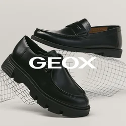 Due scarpe nere in pelle esposte su una superficie bianca, una mocassino con cuciture e una stringata con suola spessa, poggiate su una griglia di filo curva.