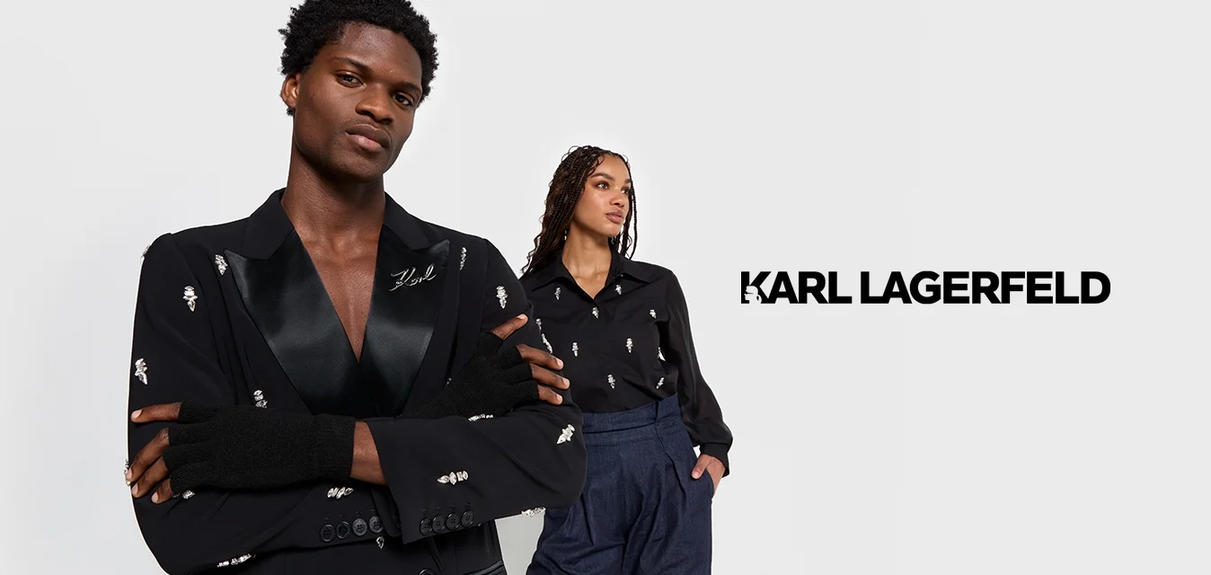 Blazer nero con colletto a scialle in satin, impreziosito da dettagli argentati. Camicia nera con abbellimenti coordinati, abbinata a pantaloni a vita alta.