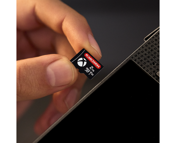 Primo piano di una scheda microSDXC Sandisk da 2 TB per Xbox, tenuta tra le dita di una persona.