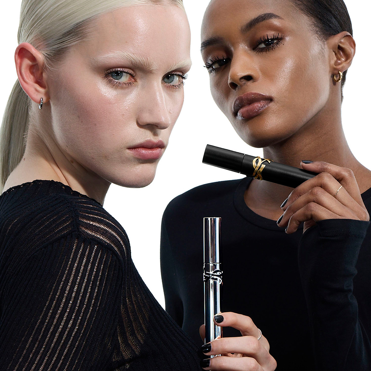 Due modelle mostrano i tubetti di mascara YSL argento e nero.