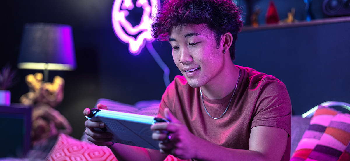 Giovane che gioca con un dispositivo di gioco portatile in una stanza illuminata al neon.