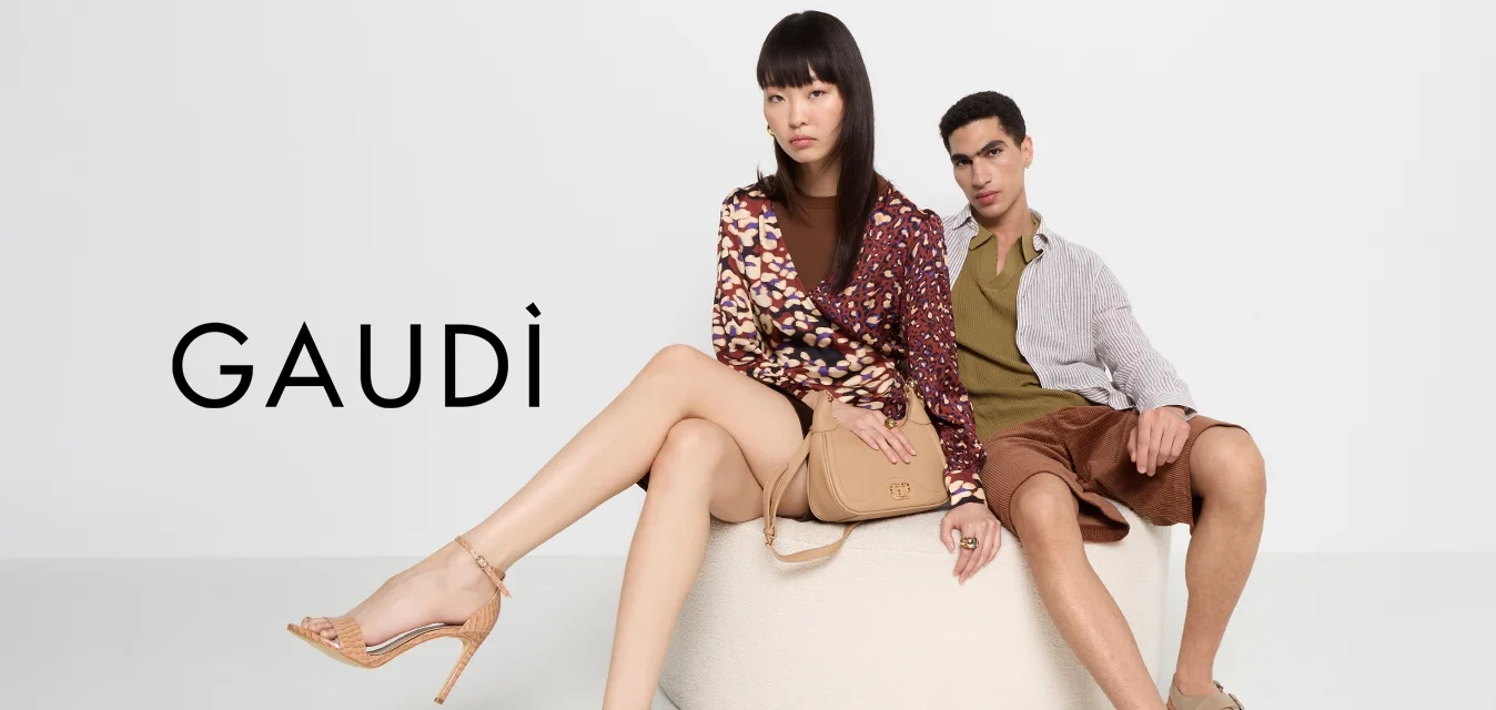 Due modelli seduti mostrano un pouf circolare di colore beige chiaro. La donna indossa una maglietta a maniche lunghe con motivo e tacchi color crema, mentre l'uomo indossa una camicia a righe e pantaloni corti marroni.