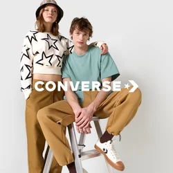 Due persone sono sedute su una scala argentata. Una indossa un maglione bianco corto con stelle nere, e l'altra una camicia verde menta e pantaloni beige.