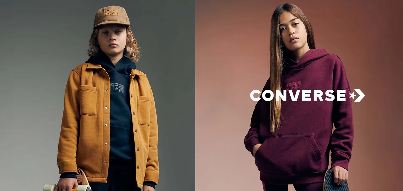 Due bambini posano con i skateboard. Il ragazzo indossa una giacca senape sopra un felpa blu navy; la ragazza indossa una felpa bordeaux con leggings abbinati.