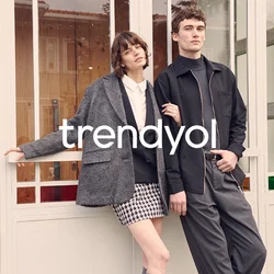 Blazer grigio oversize, camicia bianca, gonna a quadri houndstooth, calze fino al ginocchio; giacca nera con zip, pantaloni grigi; sfondo con pannelli di vetro.