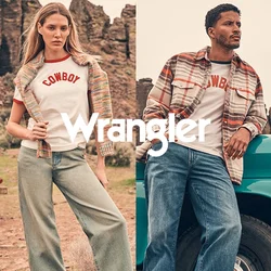 Un uomo si appoggia a un camion vintage turchese mentre una donna sta in piedi nelle vicinanze; entrambi indossano abiti casual a tema cowboy in un paesaggio desertico roccioso.