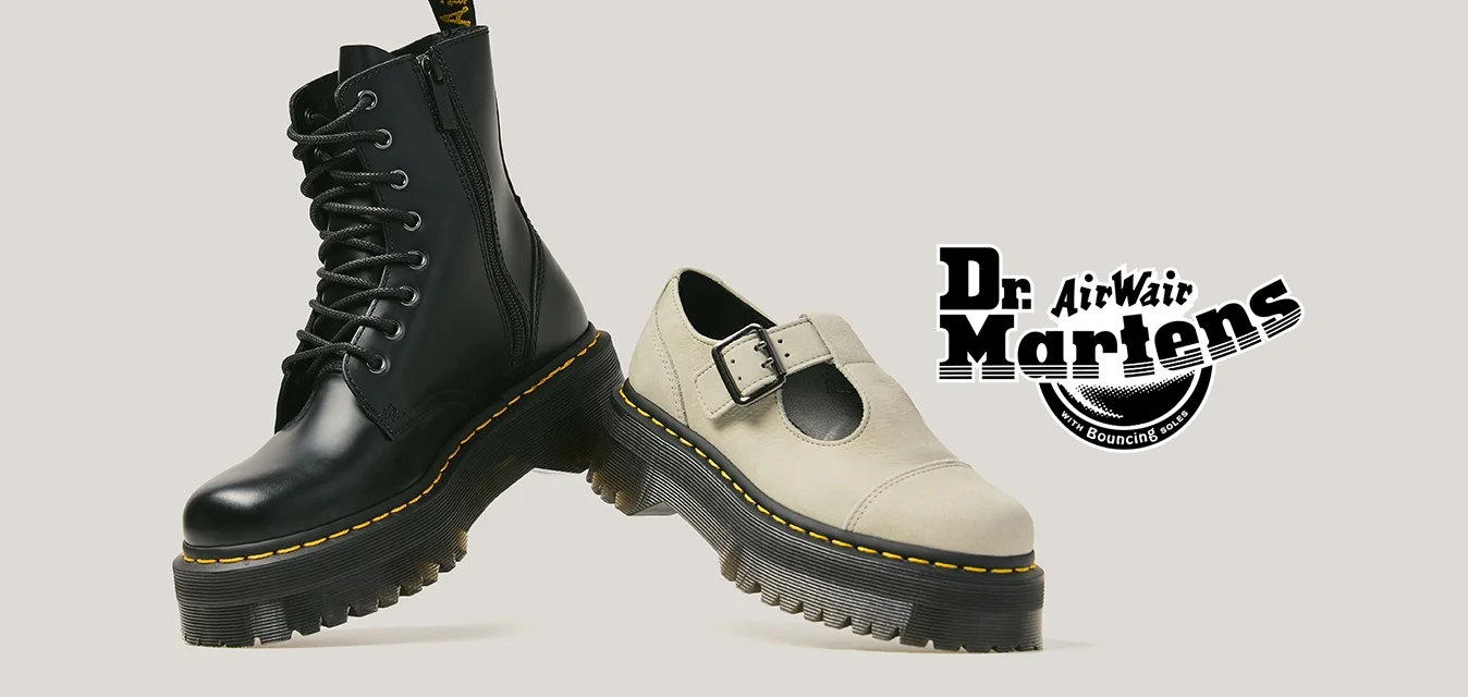 Stivale con lacci in pelle nera e scarpa Mary Jane bianca, entrambe con suole spesse con carrarmato e cuciture gialle, esposte fianco a fianco.