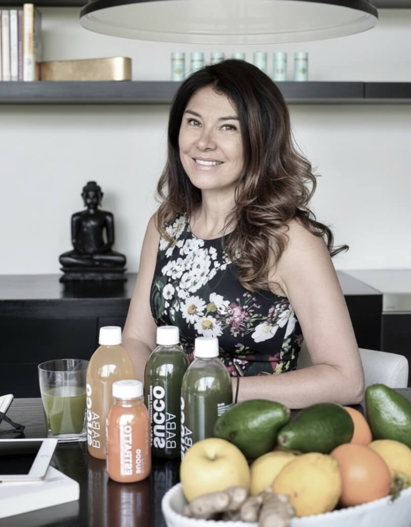 Gabriella al tavolo con bottiglie babasucco e frutta fresca davanti a sé