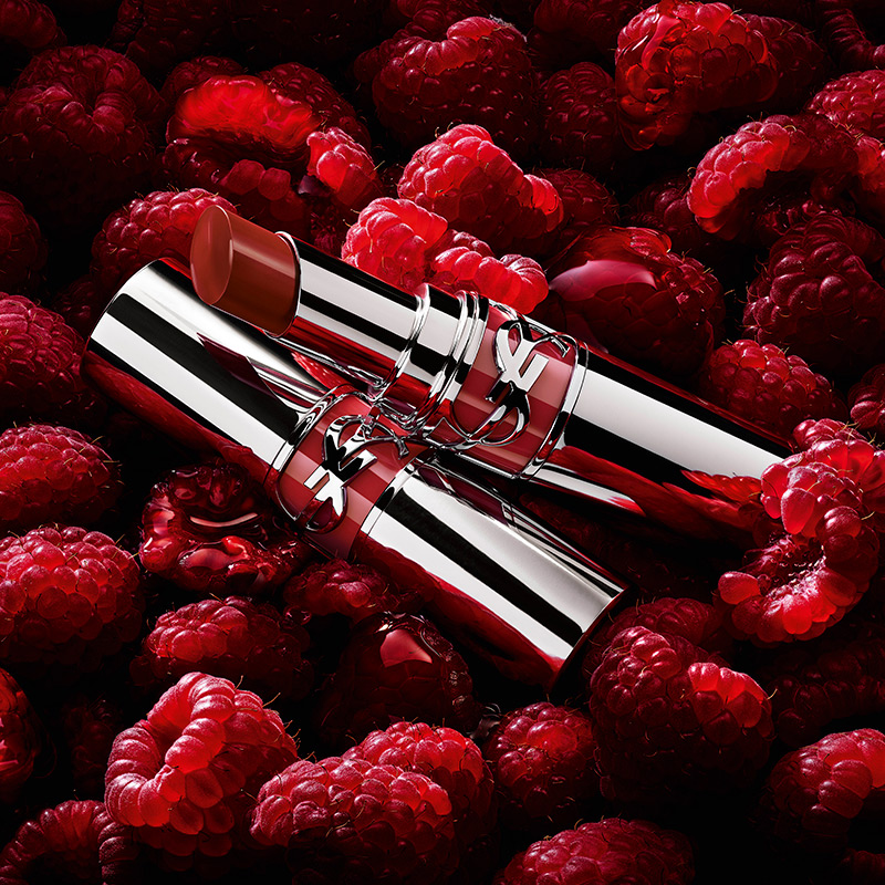 Due rossetti YSL appoggiati su un letto di lamponi freschi.