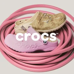 Tubo da giardino rosa arrotolato con tre scarpe di gomma usurate in tonalità beige, marrone chiaro e rosa chiaro posizionate sopra, su uno sfondo semplice.