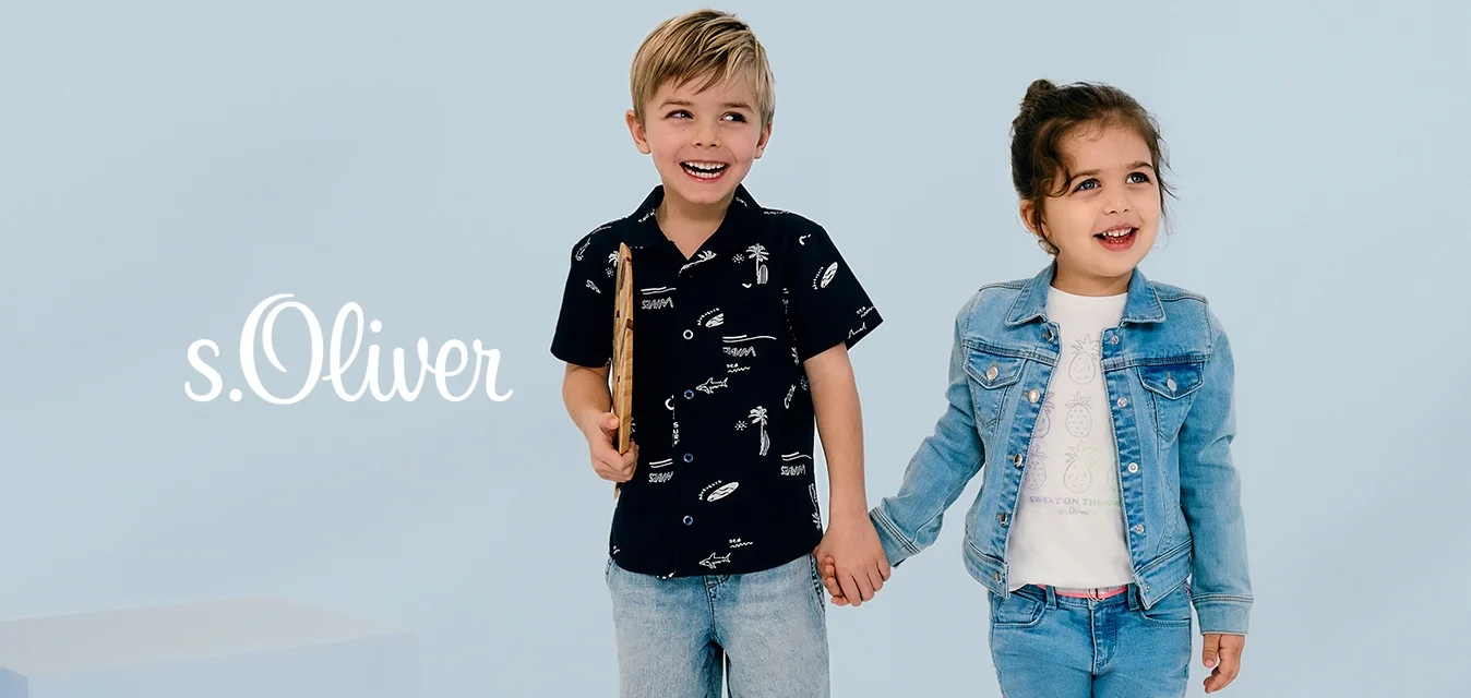 Due bambini in piedi uno accanto all'altro. Il ragazzo indossa una maglietta nera con motivi bianchi, pantaloni corti di denim e scarpe da ginnastica. La ragazza indossa una giacca azzurra, una maglietta bianca e pantaloni corti di denim.