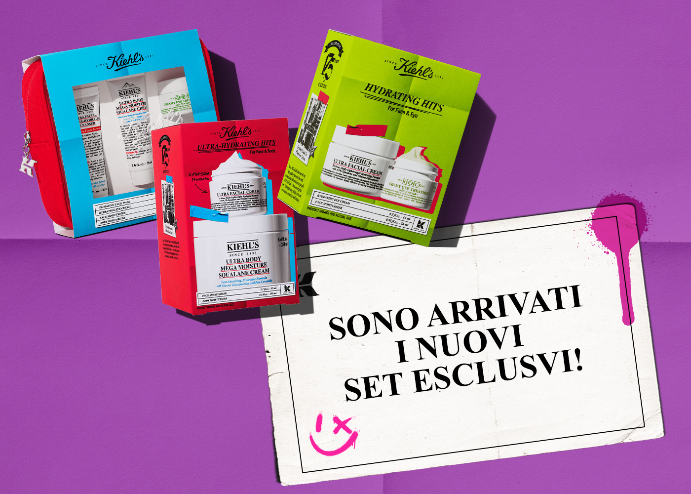 Composizione di tre set regalo Kiehl's dai colori vivaci &mdash; rosso, azzurro e verde &mdash; disposti su uno sfondo viola con un cartiglio in stile New York Apothecary che annuncia l'arrivo dei nuovi set esclusivi con uno smile disegnato a mano.