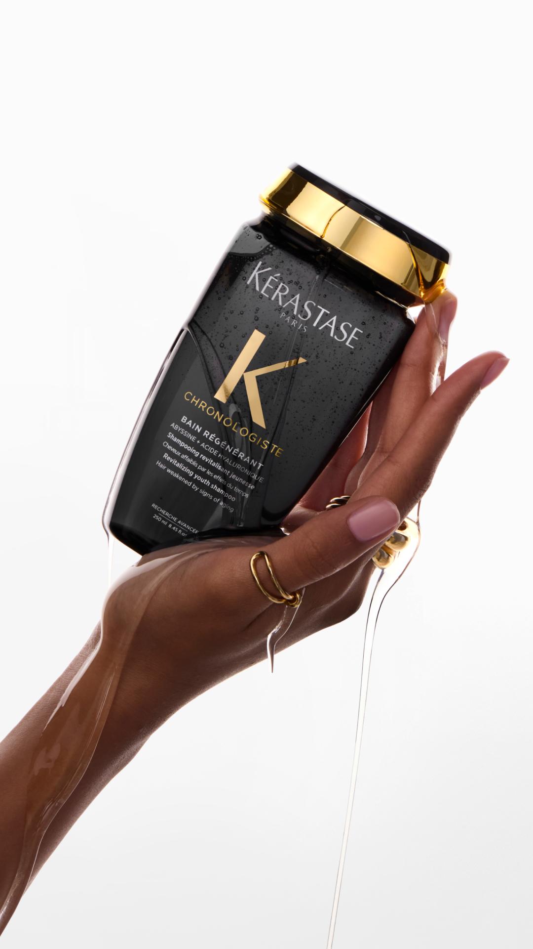 Il Bain R&eacute;vitalisant Anti-Et&agrave; Chronologiste tenuto in una mano.