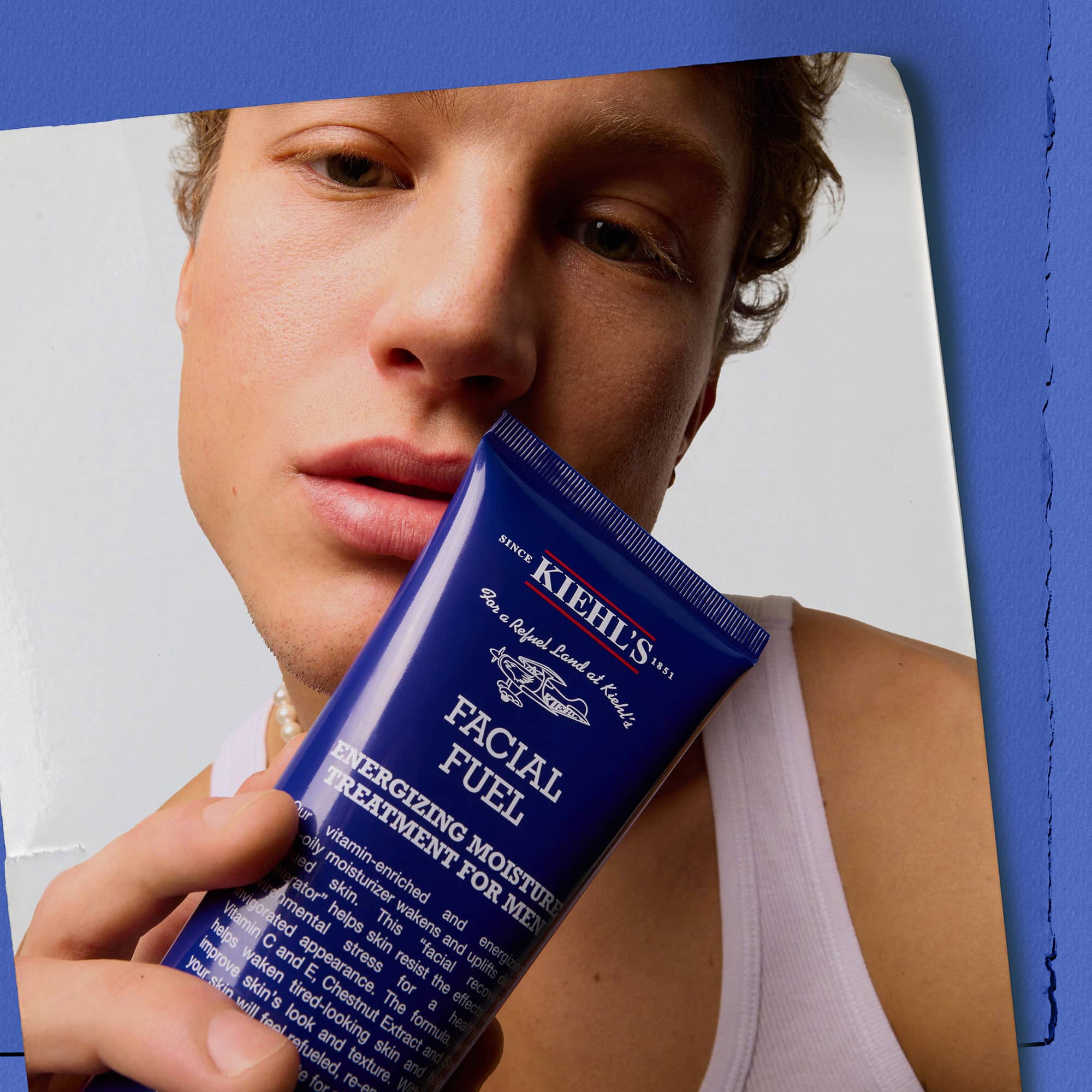 Modello uomo tiene in mano Facial Fuel Energizing Moisture Treatment Kiehl&rsquo;s in tubo blu. Trattamento idratante energizzante formulato per la pelle maschile.