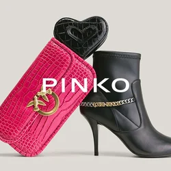 Stivaletto alla caviglia con tacco alto in pelle nera, decorato con catena dorata, accanto a una pochette rosa testurizzata con logo dorato e piccolo portamonete nero a forma di cuore all'interno.