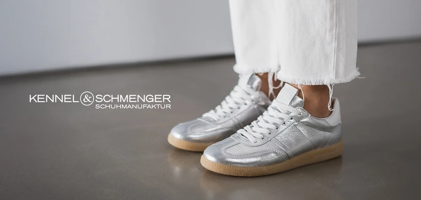 Sneakers argentati con finitura testurizzata, lacci bianchi e suole in gomma beige, abbinati a jeans in denim bianchi a metà polpaccio con orli sfrangiati.