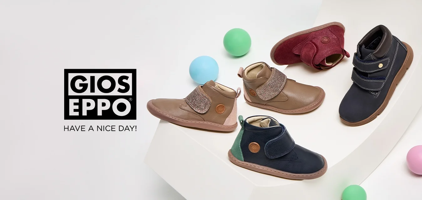 Quattro paia di stivali per bambini: in pelle marrone con fascia glitter, in suede bordeaux, blu con chiusura in Velcro e in pelle blu con dettagli verdi, su un’esposizione bianca.