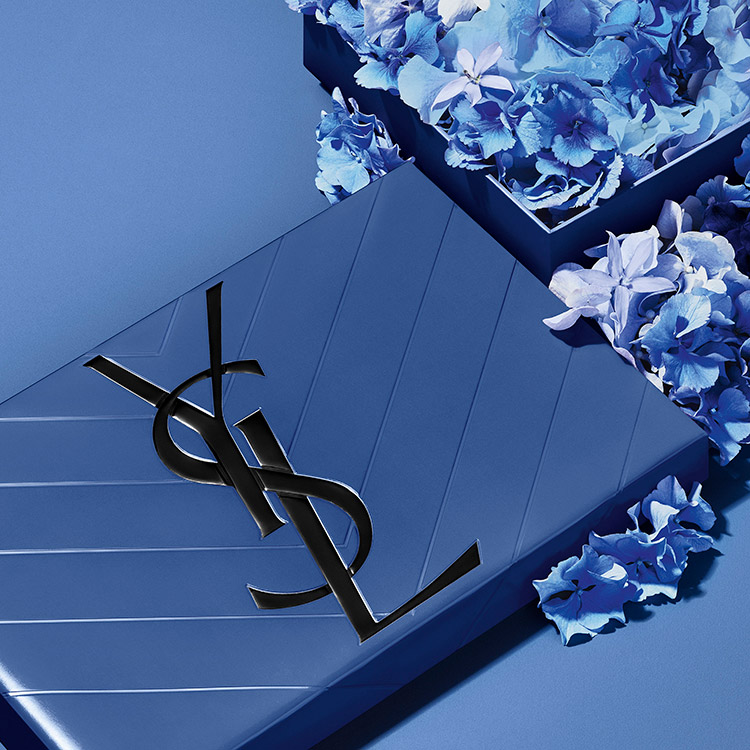 Un coffret cadeau YSL bleu matelass&eacute; accompagn&eacute; d'&eacute;l&eacute;gantes fleurs bleues.