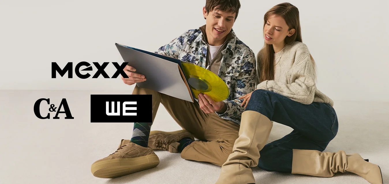 Giovane uomo e donna seduti a terra, guardano insieme un disco in vinile giallo e la sua copertina su sfondo neutro.