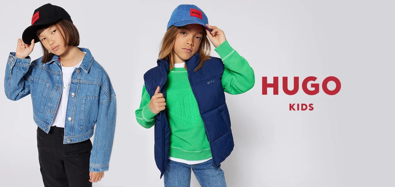 Due bambini vestiti con abiti casual in denim e cappellini, posano contro uno sfondo chiaro uniforme.