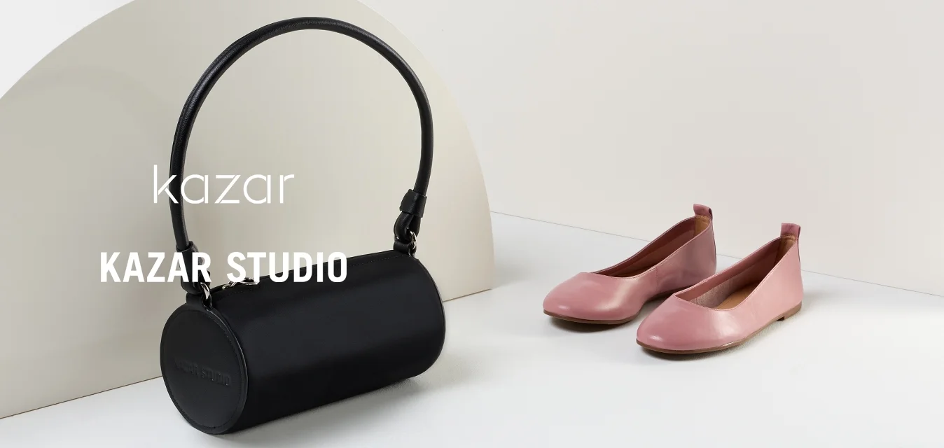 Stivale alla caviglia in pelle nera con punta a punta e tacco sottile, scarpe piatte rosa con punta arrotondata e borsa cilindrica nera con manico.