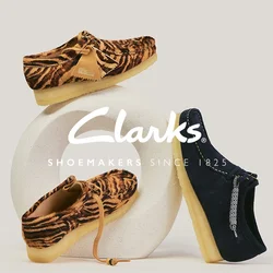 Due mocassini marroni con stampa a tigre e un mocassino blu navy con suola beige esposti su una base scultorea bianca.