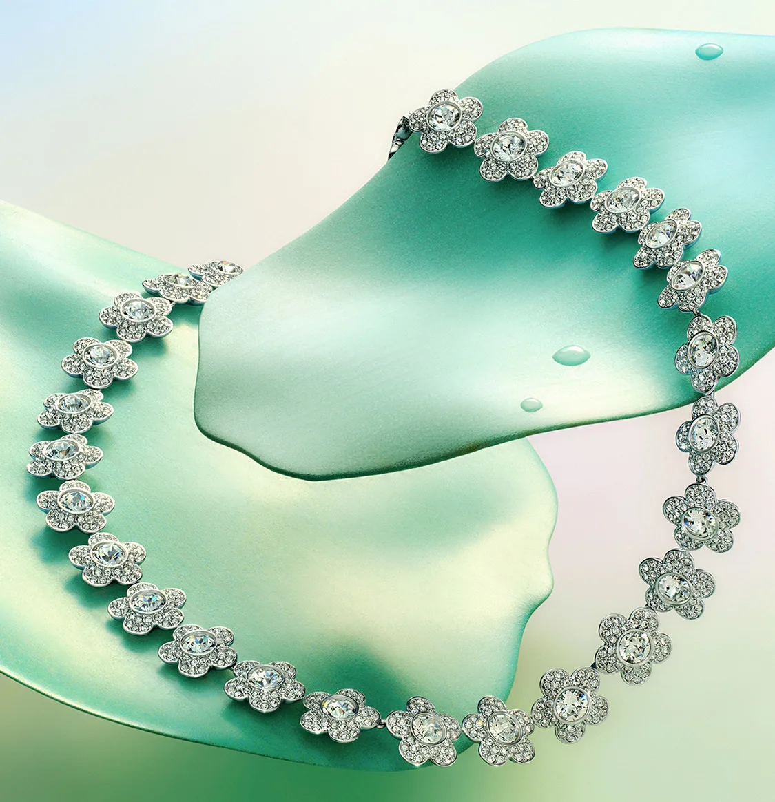 Collana Ariana Grande x Swarovski poggiata su foglie verdi