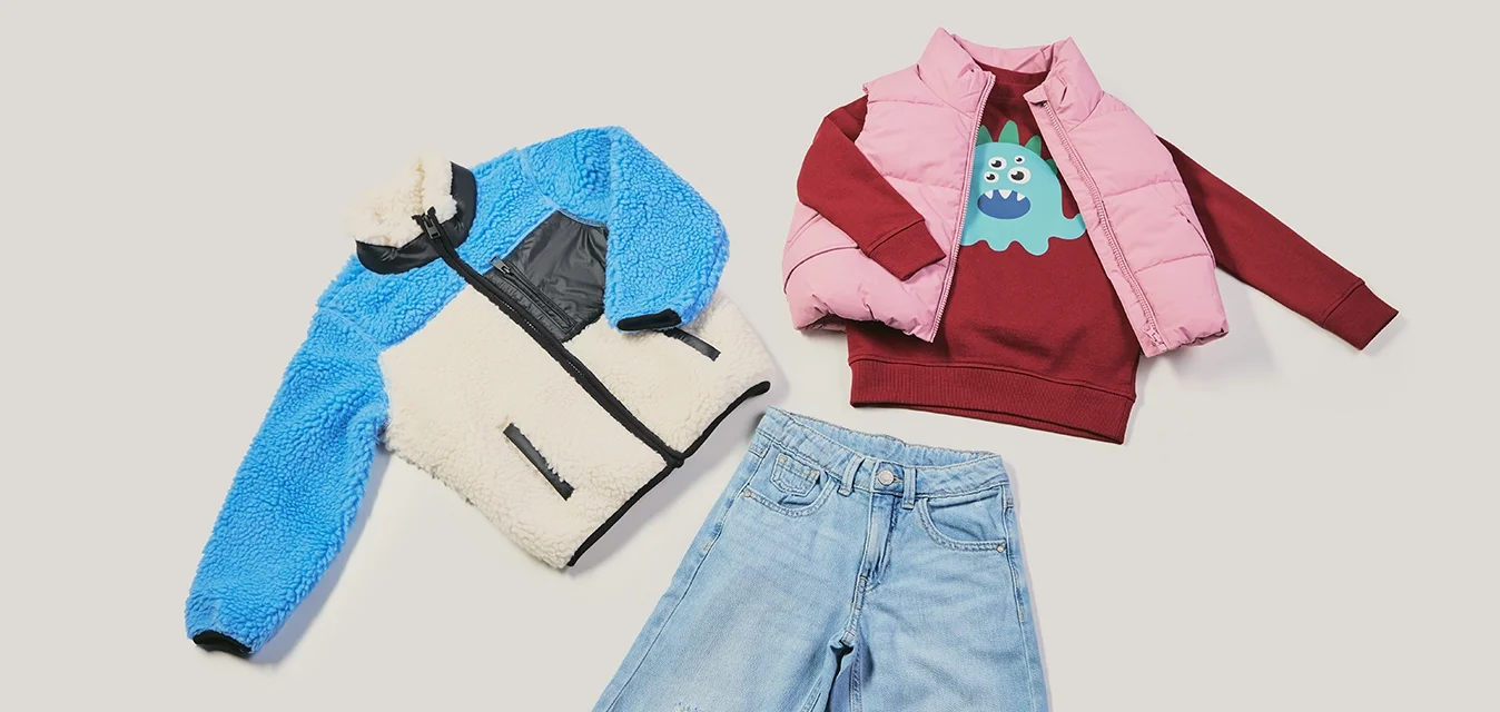 Giacca in pile blu e crema, gilet imbottito rosa, felpa bordeaux con grafica, jeans chiari strappati. Texture e colori diversi.