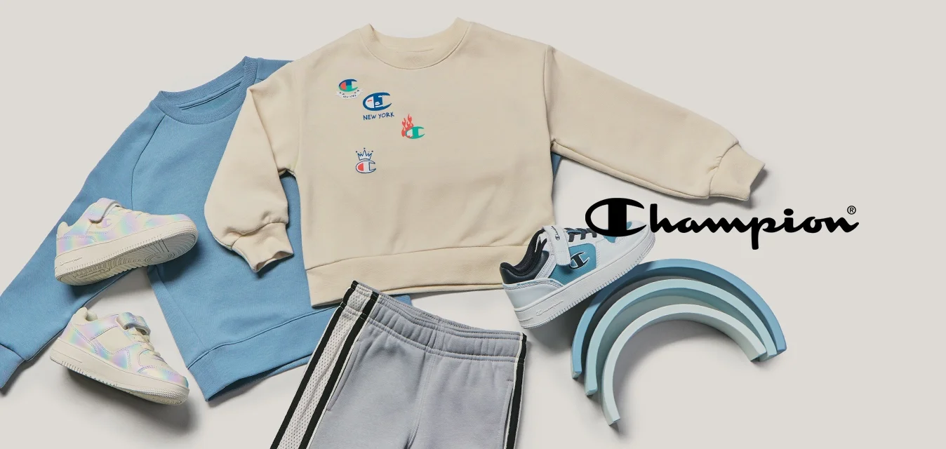 Due felpe per bambini, pantaloni della tuta grigi, tre paia di scarpe da ginnastica e una pila di giocattoli arcobaleno in legno tonali blu su uno sfondo beige.