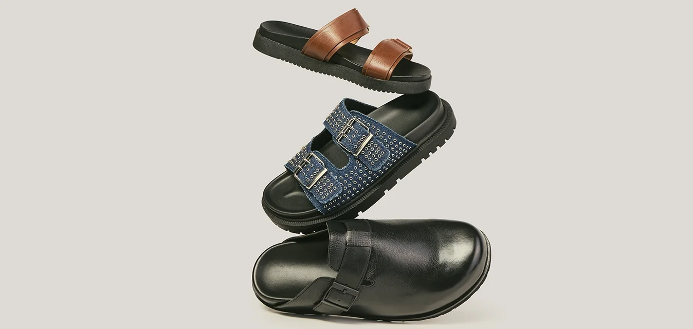 Tre sandali fluttuanti: ciabatta con stampa leopardata, sandalo marrone in pelle con fibbia e sandalo nero intrecciato con cinturini su uno sfondo chiaro.