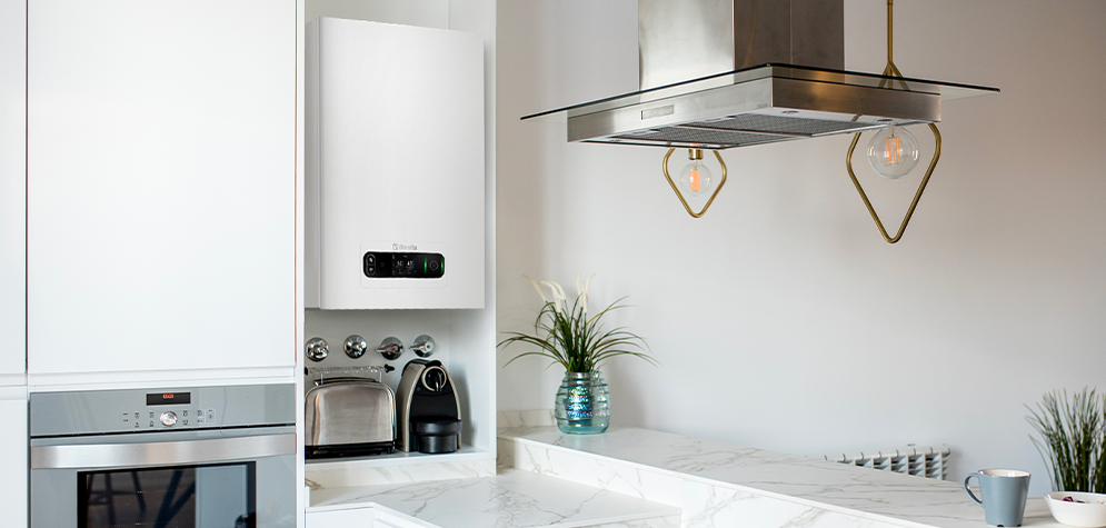 Modern white kitchen with marble worktop, stainless oven, toaster, espresso machine, wall boiler and pendant lights