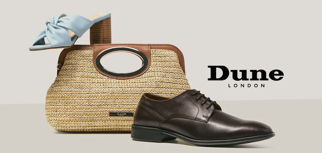 Brown woven handbag with wooden handles, blue heeled mule resting on top, and black leather men's dress shoe beside it on beige surface.