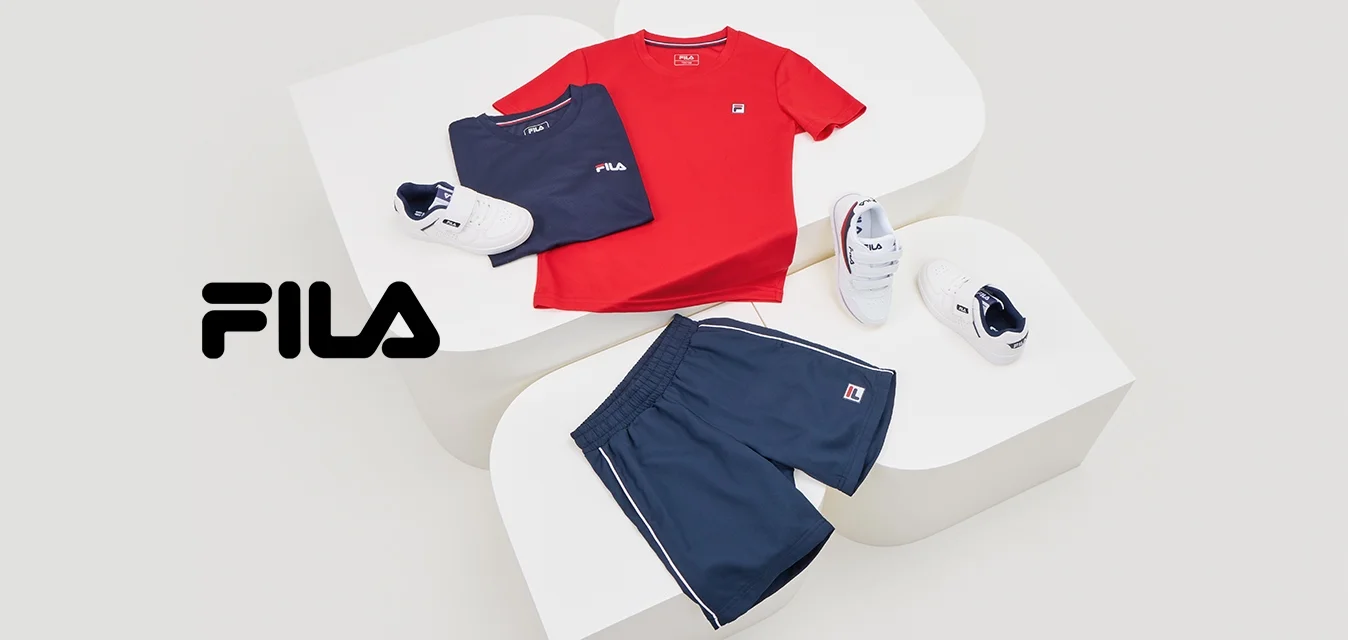 T-shirt rossa a girocollo, t-shirt blu navy, pantaloni corti blu navy, sneakers bianche con dettagli blu navy, esposti su superfici bianche. Loghi Fila visibili.