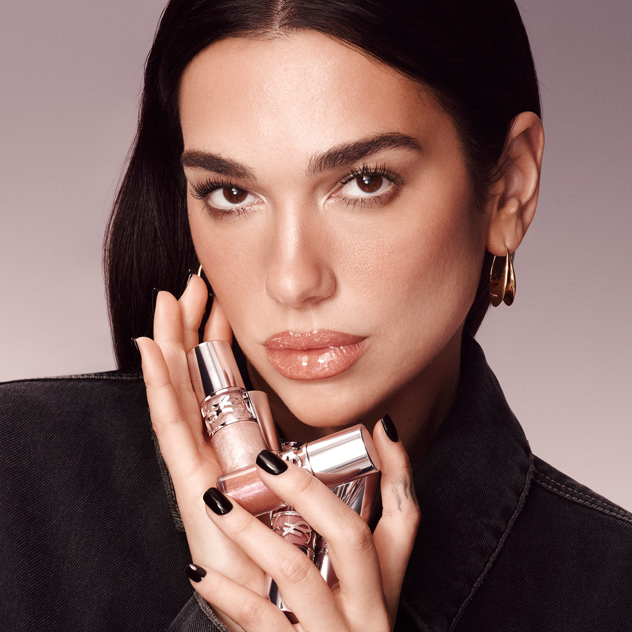 Dua Lipa con le tonalit&agrave; brillanti di YSL Beauty, trucco labbra luminoso mentre tiene un rossetto Loveshine.