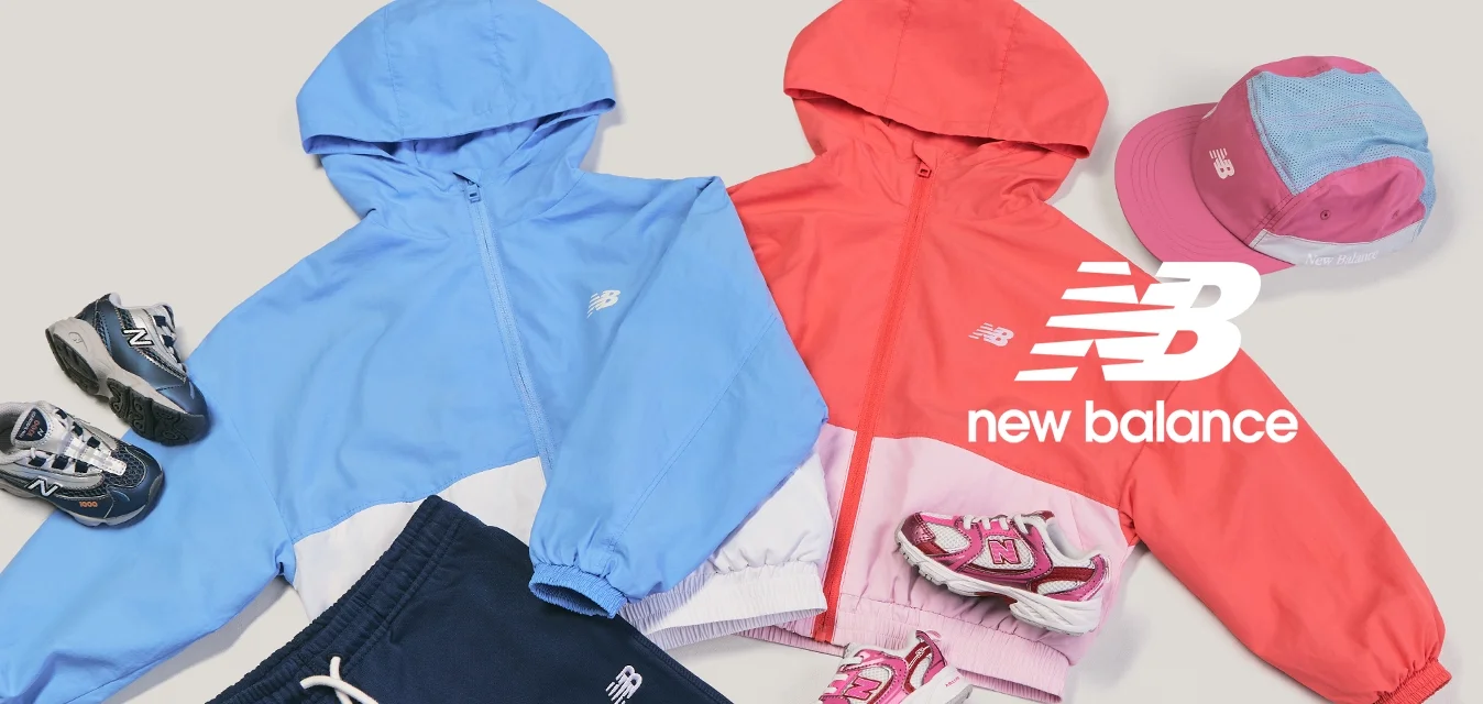 Due giacche con cappuccio per bambini, una blu e una rossa, abbinate a cappellini, scarpe da ginnastica e pantaloni blu navy, disposte su uno sfondo chiaro.