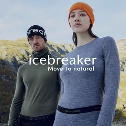 Due adulti con abbigliamento da esterno, indossano strati base con il marchio e berretto, posano davanti a un paesaggio montano sotto un cielo limpido.